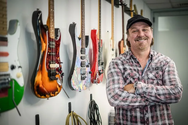 Alfredo Alonso posando junto a su colección de guitarras