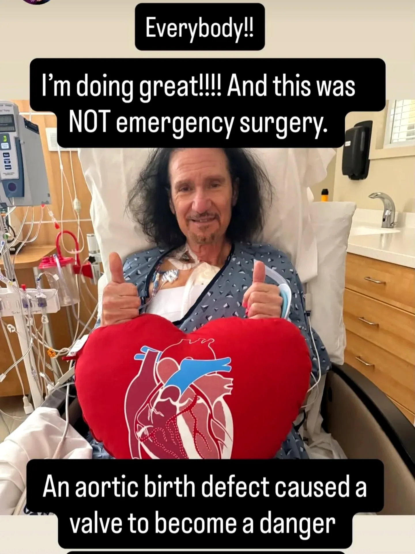 Bruce Kulick en su cama de hospital, haciendo la señal de pulgares arriba tras su cirugía de corazón