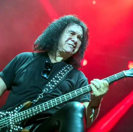 Gene Simmons sonriendo mientras toca el bajo en vivo