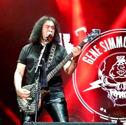 Gene Simmons tocando el bajo frente al logo de la Gene Simmons Band