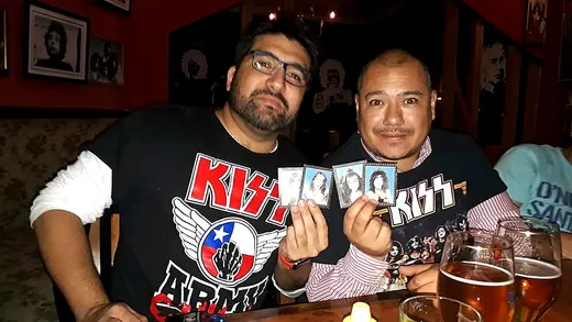 Dos fans mostrando tarjetas coleccionables de KISS