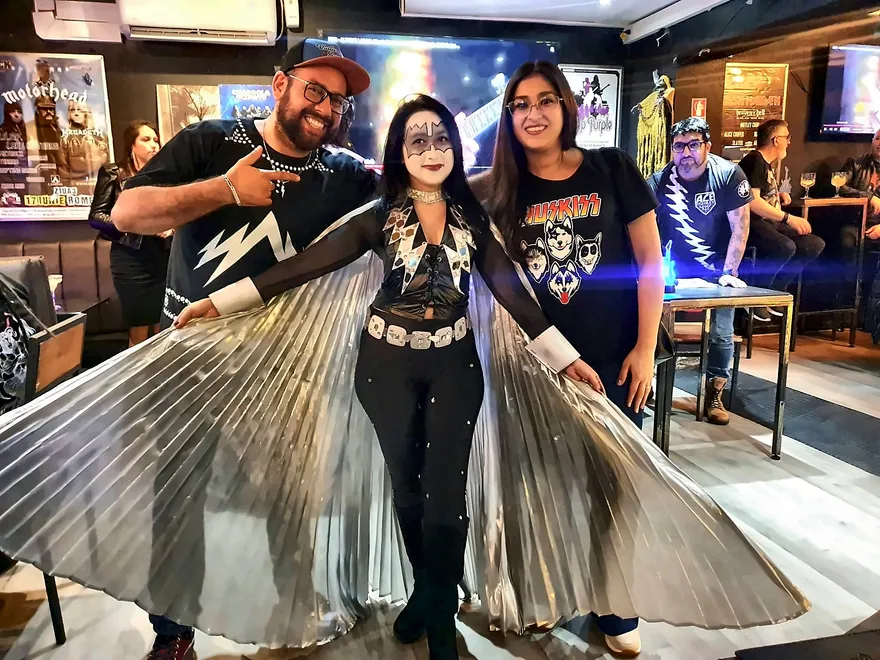 Fan caracterizada como Ace Frehley con alas plateadas, junto a dos asistentes del homenaje