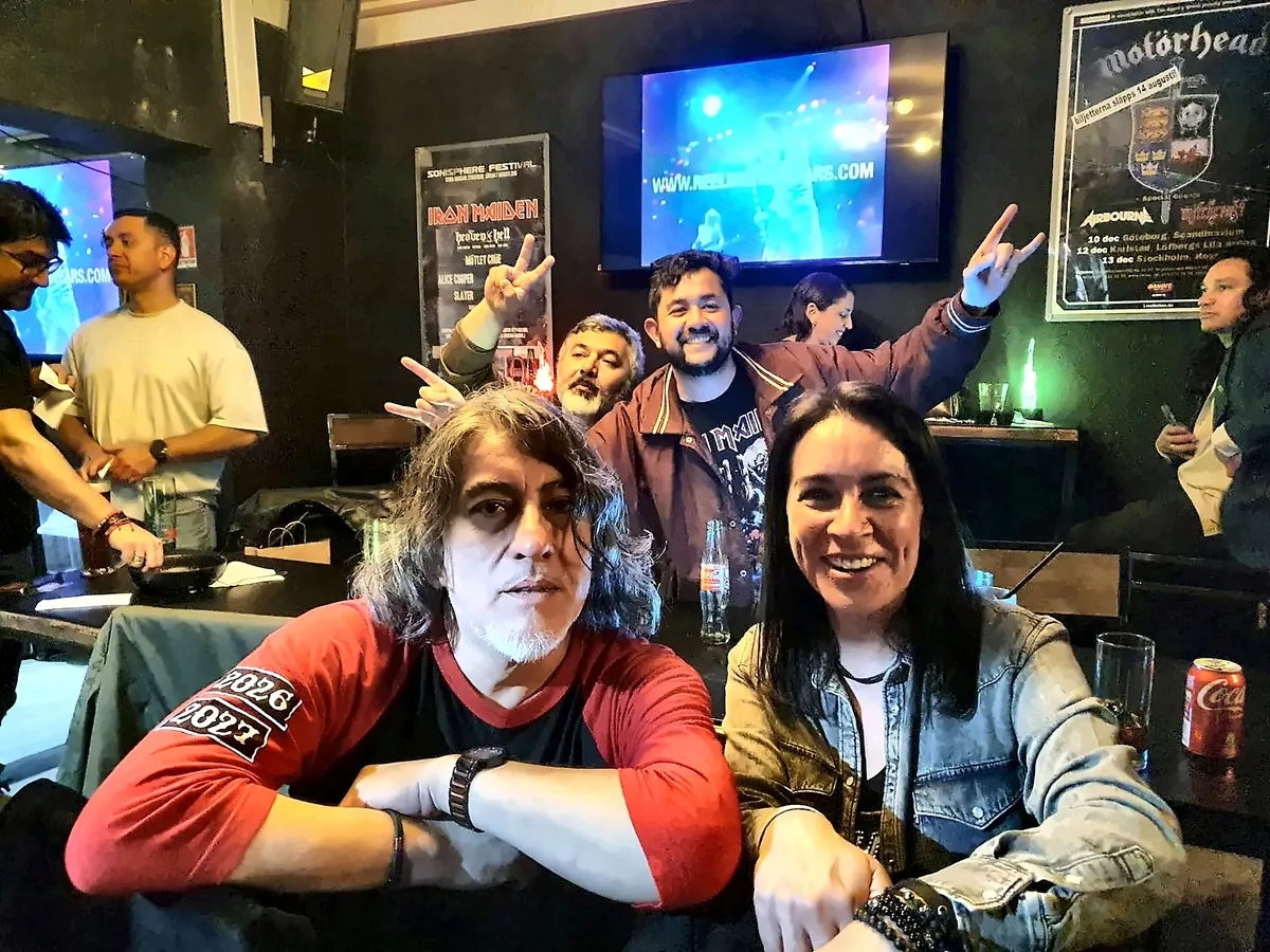 Asistentes sonriendo y haciendo cuernos de rock en una mesa de Chargobar