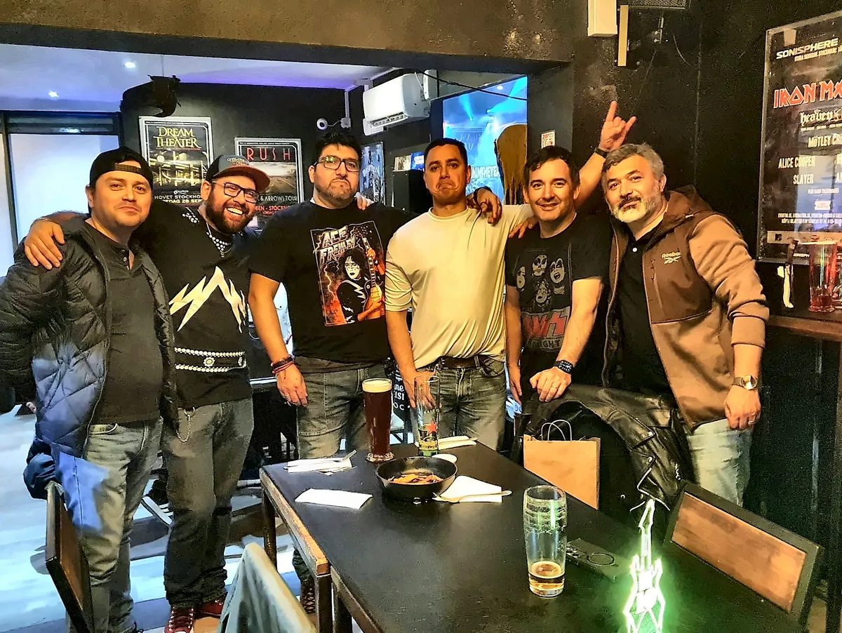 Seis kisseros posando juntos en Chargobar, uno de ellos con una polera de Ace Frehley, en el homenaje al Spaceman