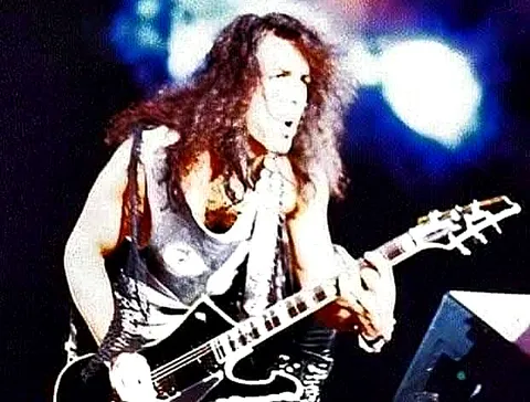 Bruce Kulick tocando la guitarra bajo luces azules, concierto de Chile 1994