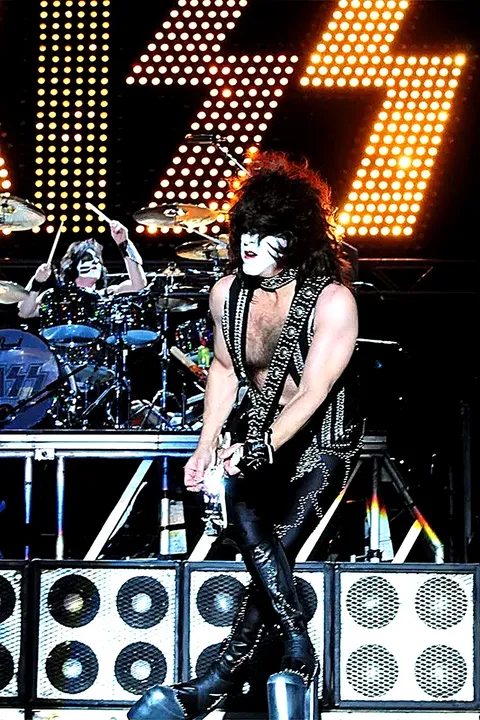 Paul Stanley caminando por el escenario, con Eric Singer tocando la batería al fondo