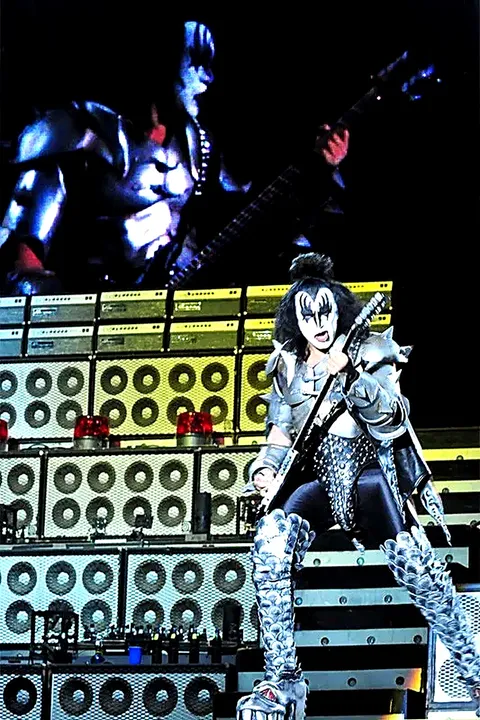 Gene Simmons tocando el bajo, con su imagen proyectada en la pantalla gigante