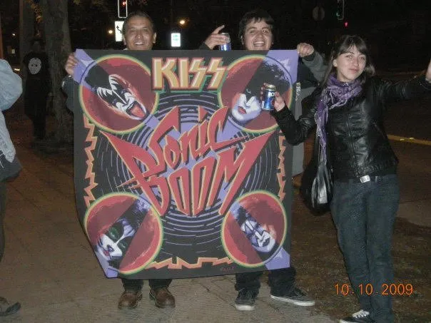 Fans de KISS Army Chile posando con el banderín de Sonic Boom en la calle, después del evento