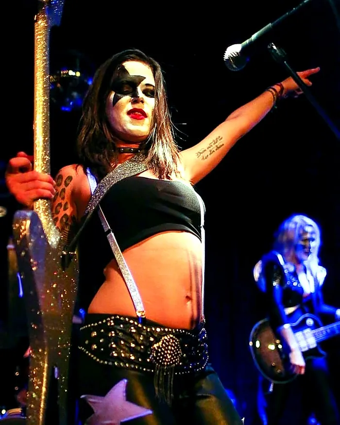 Moa Muñoz con maquillaje estilo Catman apoyada en su guitarra sobre el escenario