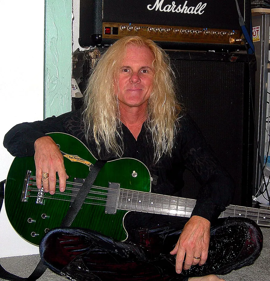 Tod Howarth posando con una guitarra verde frente a un amplificador Marshall