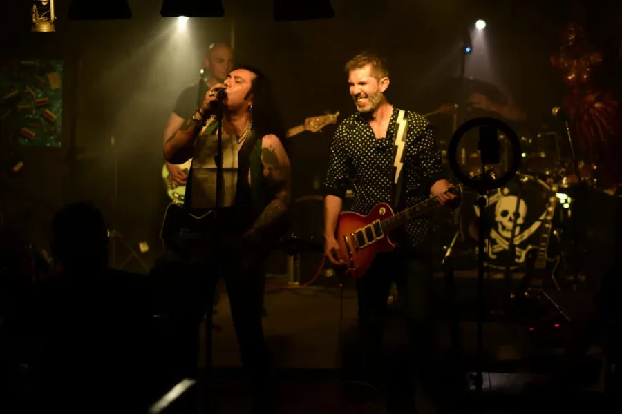 War Machine tocando en vivo, vocalista y guitarrista frente a una batería con bandera pirata