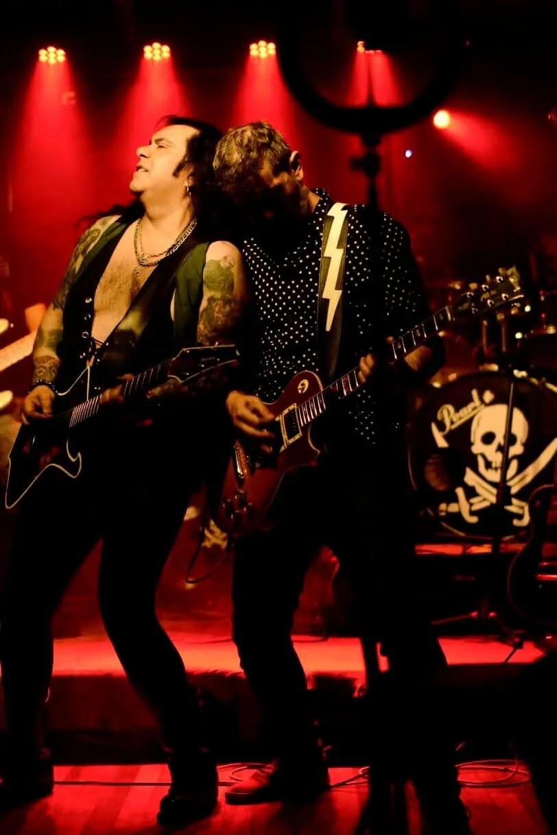 El vocalista de War Machine cantando junto al guitarrista, iluminados por luces rojas
