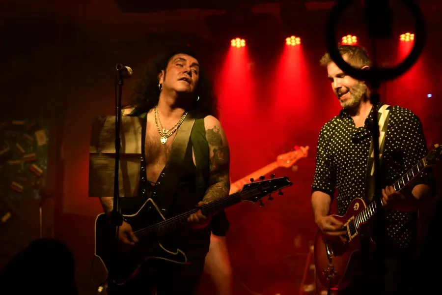 El vocalista de War Machine sosteniendo la letra en el atril del micrófono, junto al guitarrista sonriendo